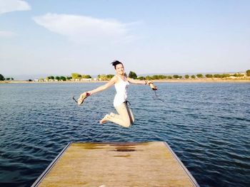 Woman jumping on boat against sky