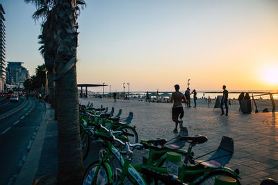 People by sea against clear sky during sunset