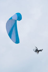 Low angle view of person powered paragliding against sky