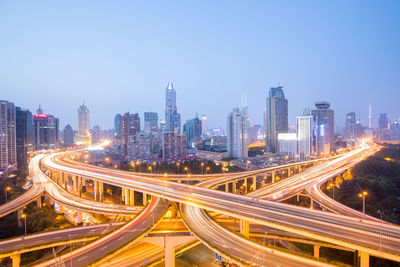 High angle view of light trails on road amidst buildings in city against sky