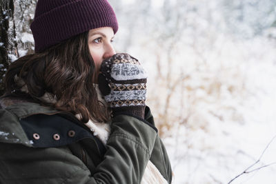 Portrait of woman wearing hat against trees during winter