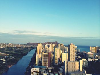 City at waterfront against blue sky