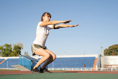 Full length of woman jumping against clear blue sky