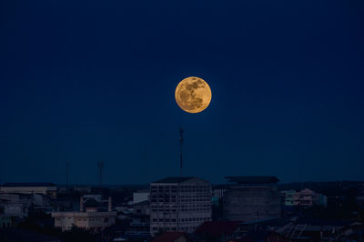 Townscape against clear sky with moon at night