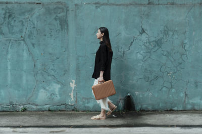 Side view of woman standing against wall