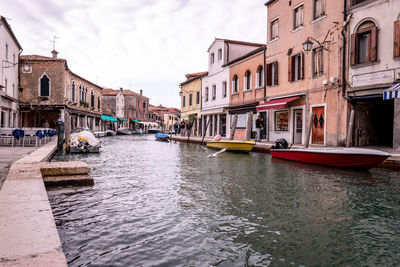 Boats in canal amidst buildings in city
