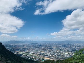 High angle view of city buildings against cloudy sky