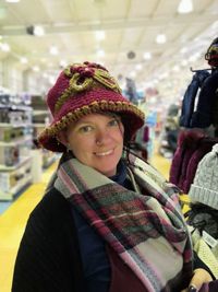 Portrait of smiling woman wearing hat and scarf at store