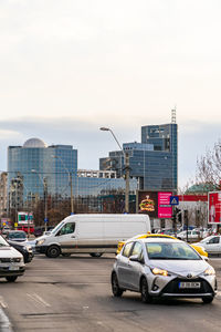 Cars on road by buildings against sky