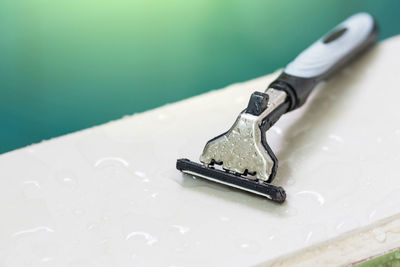 Close-up of razor over wet white table