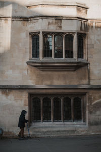 Rear view of woman standing outside old building
