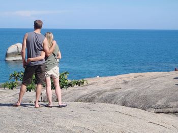 Rear view full length of couple standing against sea