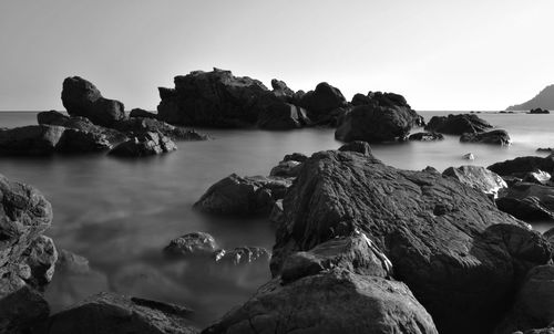 Scenic view of rocks in sea against clear sky