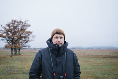 Portrait of man standing on field against sky during winter