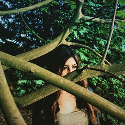 Woman looking away while standing by tree