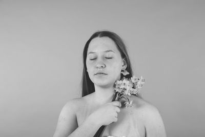 Shirtless girl with flower against gray background