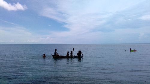 People in sea against sky