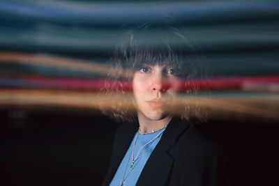 Portrait of woman standing against black background