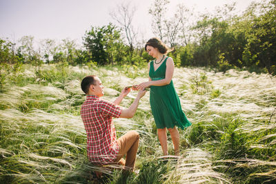 Couple holding plants while standing on grassy land