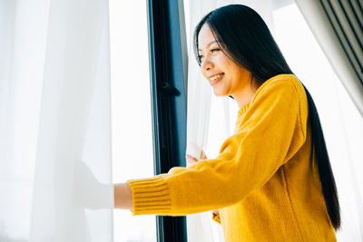 Young woman looking through window