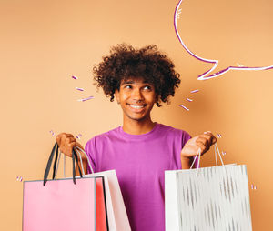 Portrait of smiling young woman using digital tablet while standing against pink background