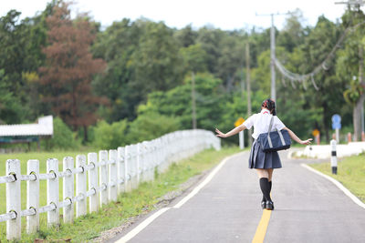 Rear view of woman walking on road