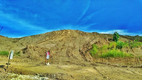 Rear view of man walking on mountain against blue sky