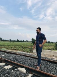 Man standing on railroad track against sky