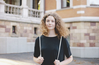 Portrait of young female student standing outside university