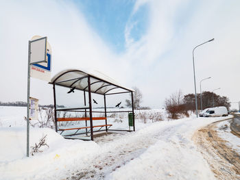 Road sign on snow covered field against sky