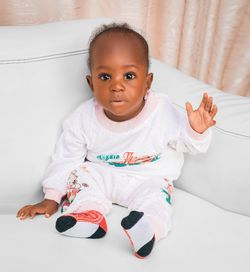 Portrait of cute baby boy with teddy bear on bed at home