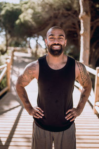 Portrait of man smiling while standing on footbridge