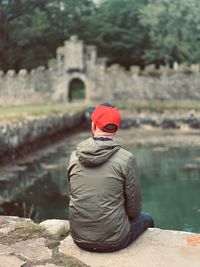 Rear view of man sitting on rock