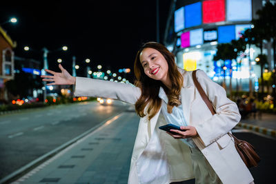 Portrait of young woman standing in city at night