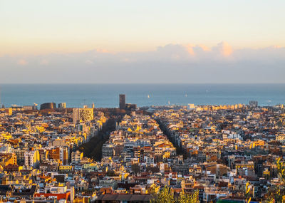 High angle view of city by sea against sky during sunset