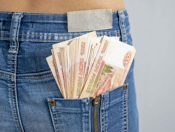 Midsection of woman holding paper currency in jeans
