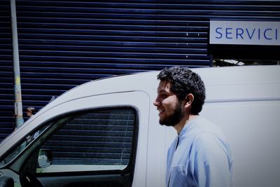 Portrait of young man looking through car window