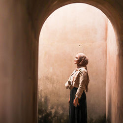 Woman looking at camera while standing against wall