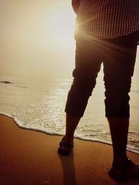 Low section of man standing on beach