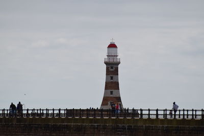 View of lighthouse by building against sky