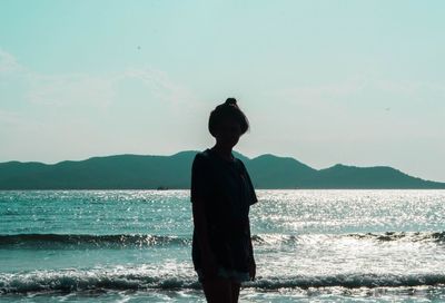 Silhouette woman standing at beach against sky