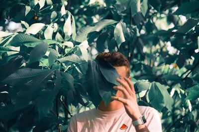 Portrait of young man with leaves on tree