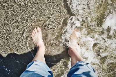 Low section of person in sea during sunny day