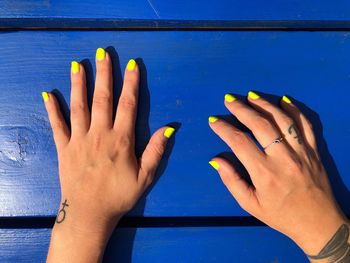 Cropped hands of mid adult woman with yellow nail polish on table