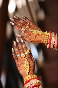 Cropped hands of bride with henna tattoo and jewelry