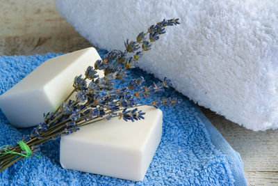 High angle view of soaps with rolled up towels and lavender flowers on table