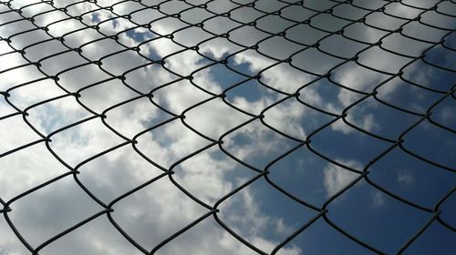 Low angle view of chainlink fence against sky