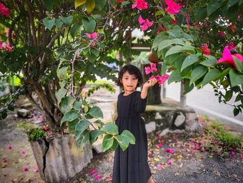 Portrait of woman standing by pink flowering plants