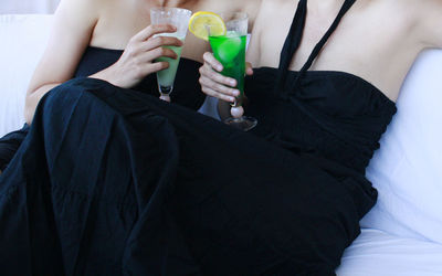 Midsection of lesbian couple having drink at home