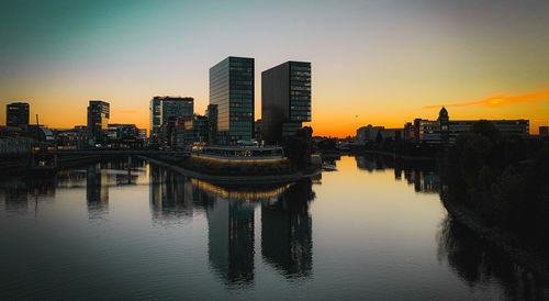 Reflection of illuminated buildings against sky during sunset